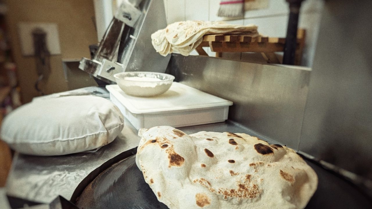 Fresh Saj bread puffing on a hot cooking surface.
