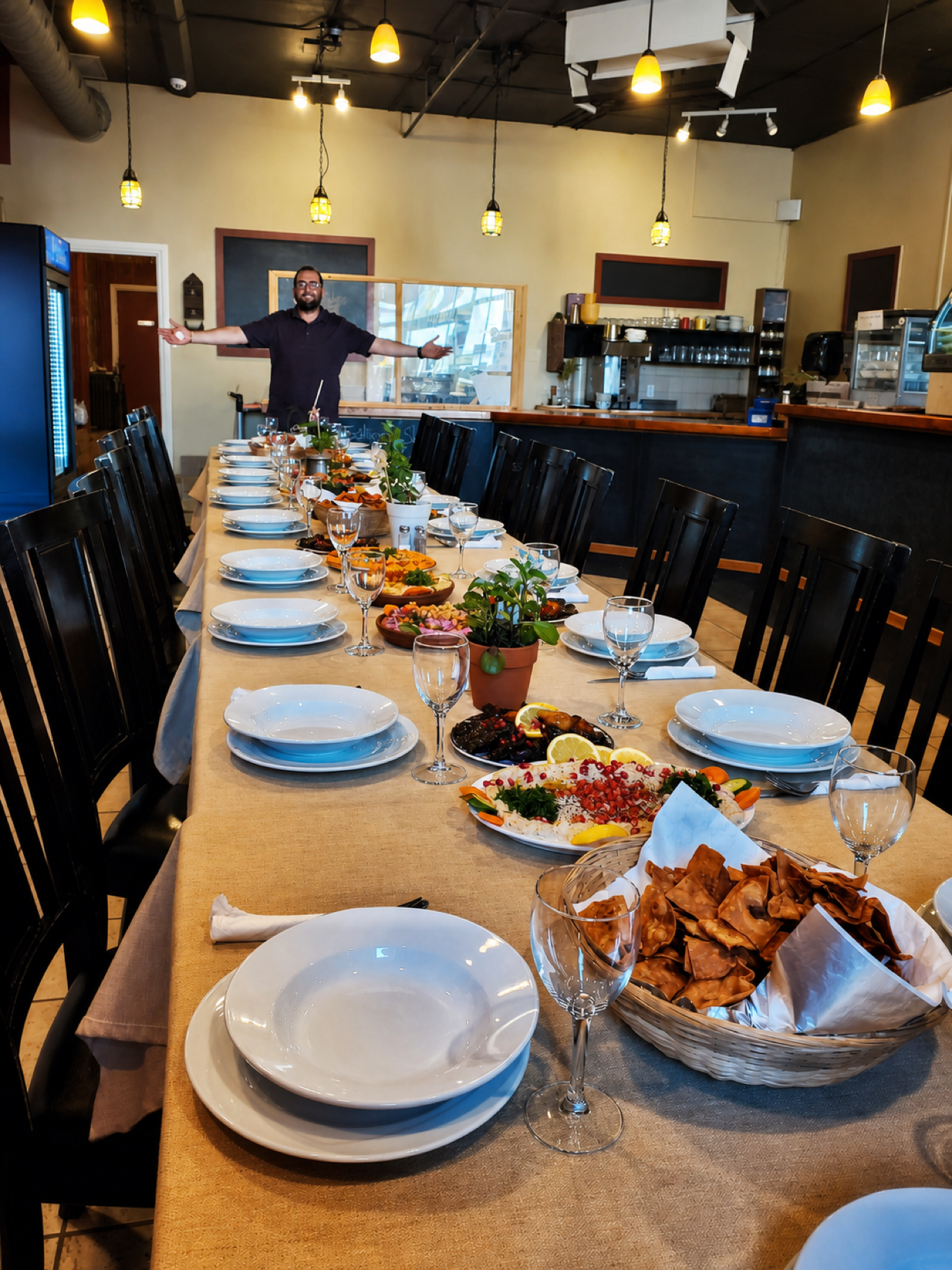 George welcoming guests from the end of a table set for a meal at Georgie's.